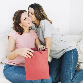 mulher-beijando-mulher-com-saco-de-papel-vermelho
